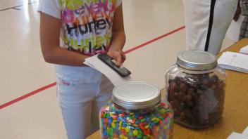 Children counting candy in a jar.
